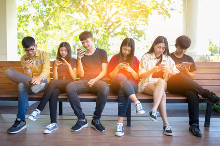 Closeup group adult hipsters friends sitting sofa using hands modern smartphone tablet.Business startup friendship teamwork conceptの写真素材
