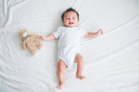 Portrait of a crawling baby on the bed in her room, Adorable baby boy in white sunny bedroom, Newborn child relaxing in bedの写真素材