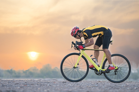 Road bike cyclist man cycling. Biking sports fitness athlete riding bike on an open road to the sunset.の写真素材