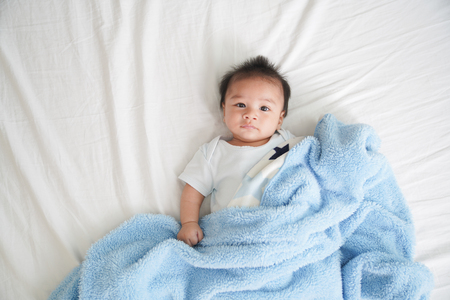 Portrait of a crawling baby on the bed in her room, Adorable baby boy in white sunny bedroom, Newborn child relaxing in bed, Textile and bedding for kidsの写真素材