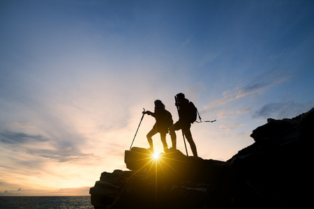 Asia couple hiking help each other silhouette in mountains with sunlight. couple hiking help each other silhouette in mountains with sunlightの写真素材