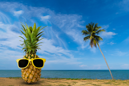 Tropical summer delights, Fresh pineapple on the beach, Fashion hipster pineapple, Bright summer color, Tropical fruit with sunglasses, Creative artの写真素材