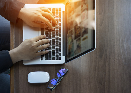Businessman at work. Close-up top view of man working on laptop while sitting at the wooden deskの写真素材
