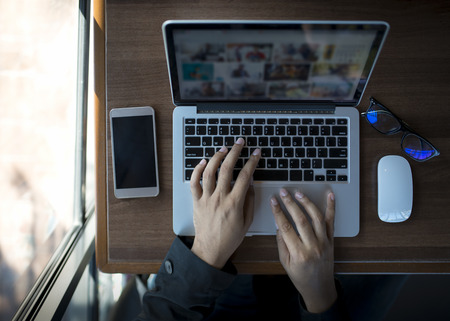 Businessman at work. Close-up top view of man working on laptop while sitting at the wooden deskの写真素材