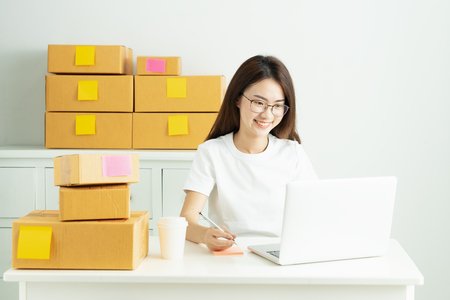 Young asian girl is freelancer with her private business at home office, Working with laptop, Coffee, Online marketing, Customer order and packaging or packing.の写真素材