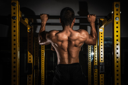 Rear view of healthy muscular young man with his arms stretched out, Strong athletic man fitness...