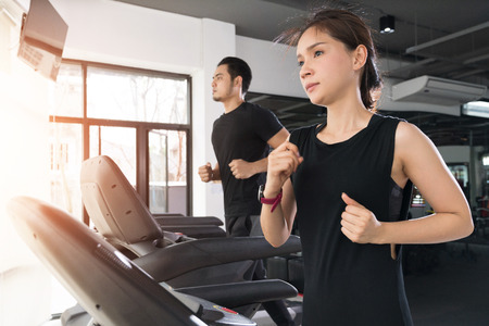 Running on treadmills, Active young woman and man running on treadmill in gymの写真素材