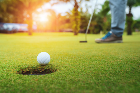 Golfer putting golf ball on the green golf, lens flare on sun set evening time, Pro Golf long putting golf ball in to the hole, sunset scene time.の写真素材