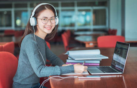 Back to school education knowledge college university concept, Beautiful smiling female student using online education service, Young woman looking in laptop display watching training and listeningの写真素材