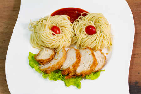 The spaghetti, fried chicken on white plate on wood backgroundの写真素材