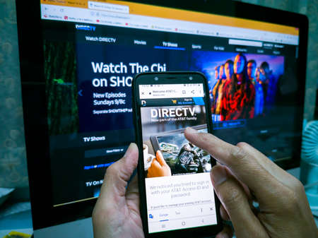 Asian hands, using mobile phone, connected to monitor or TV,
To watch movies Direc TV, on vacation, after work, inside the house. Bangkok, Thailand 19 August 2021.のeditorial素材