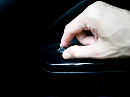 The man's hand is adjusting the side mirror with the knob in the desired direction.