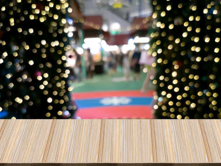 Artificial wood tables in front, behind bokeh blur, are trees, lights and entrance-exit. Exhibitions...