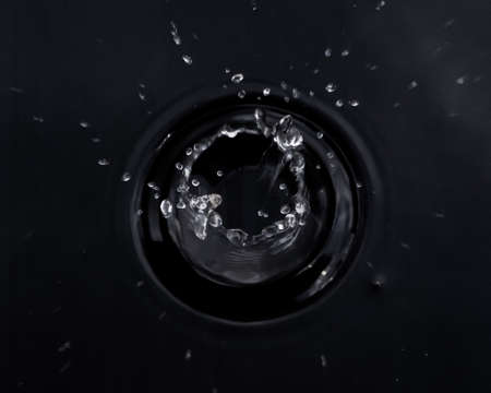 Drops of water droplets scattered around in a circle on a black background.の写真素材