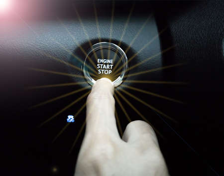 Fingers pressed on the start and stop switch, with an orange glow, and the sun's rays.