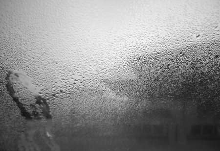 Dew or water drops on window and the whole area. Water drops on the glass with a black backgroundの写真素材