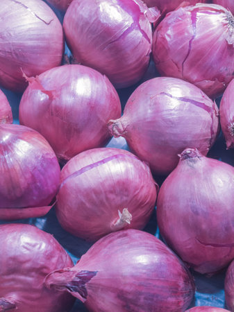 Stack of fresh red onions in supermarket. Close-up of fresh red vegetarian food.の写真素材