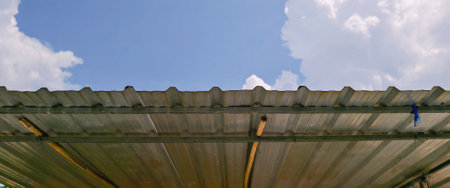 Low angle view of metal sheet roof of parking lot and raindrops behind is dark sky