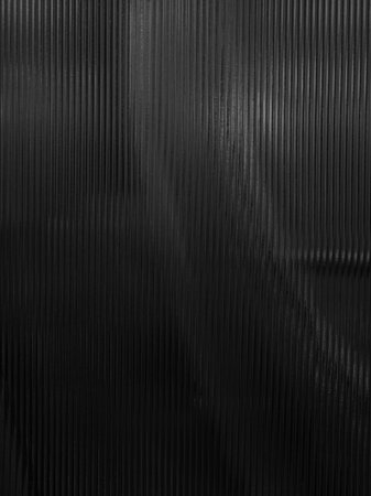 Dark surface of frosted glass with straight line pattern with shadows and reflections.の写真素材