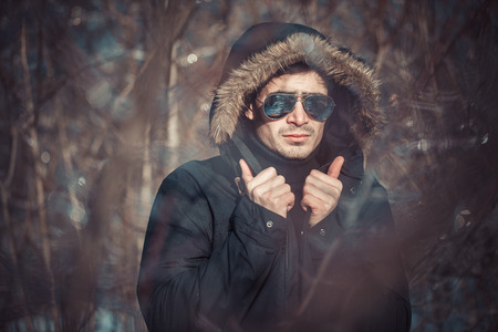 a handsome young man with spectacles in the Park in winterの写真素材