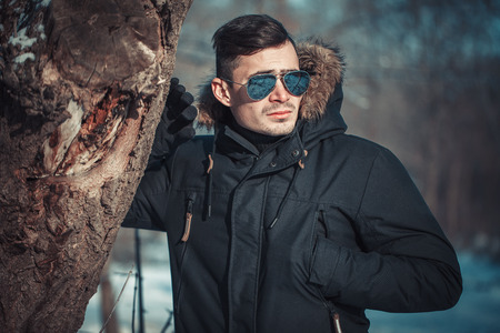 a handsome young man with spectacles in the Park in winterの写真素材