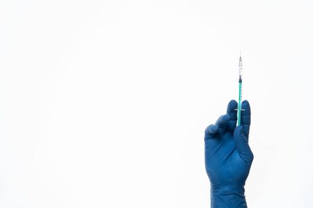 Hand in a blue glove holding syringe isolated on white.の写真素材