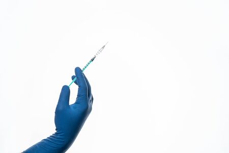 Hand in a blue glove holding syringe isolated on white.の写真素材