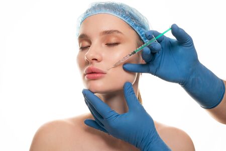 Young beautiful woman receiving a cosmetic botox injection in her face, close upの写真素材