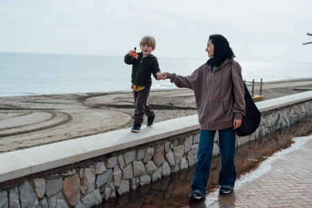 mother and son walk along the embankment. they hold hands and smileの写真素材