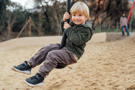 Little boy riding on a makeshift swing in the park .Mom looks at the flight of a little son.