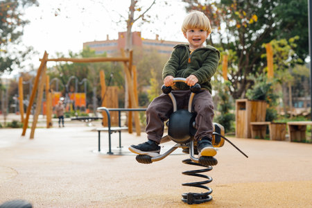 A little boy rides on a swing on a spring and smilesの写真素材