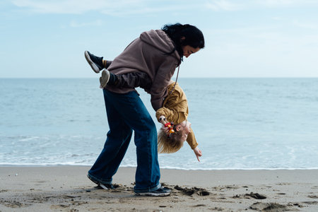 Happy mother running along the beach with her son, enjoying by the seaの写真素材