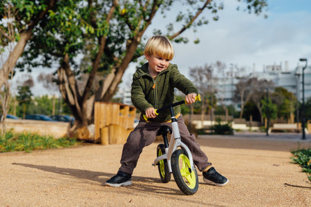 A little boy is on a bike ride.3 year old blond boy plays and enjoys a sunny day in the park on a bicycleの写真素材