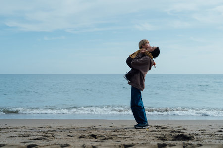 Happy mother running along the beach with her son, enjoying by the seaの写真素材