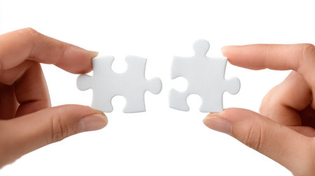 Two hands are holding two blank puzzle pieces, illustrating the concept of teamwork and collaboration in problem-solving and creative endeavors across various fields.の素材