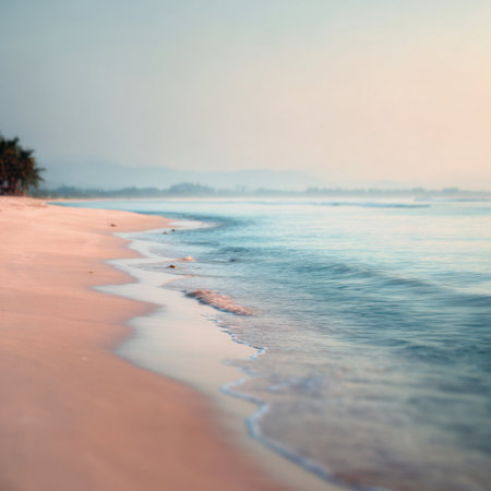 A tranquil beach scene at sunrise with gentle waves lapping at the shoreline. This image captures the beauty of nature, perfect for themes of relaxation and travel.の素材