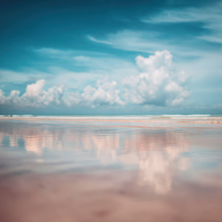 A stunning view of a calm ocean shoreline under a clear blue sky. Soft fluffy clouds stretch across the horizon, perfectly reflecting on the peaceful waters. Ideal for relaxation.の素材
