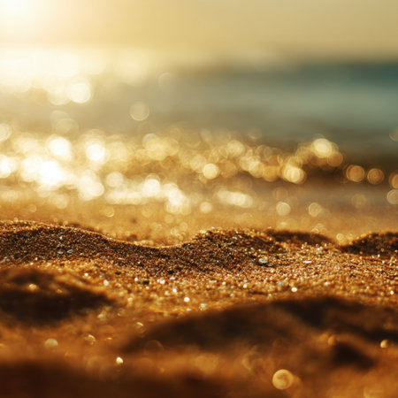 A serene beach scene captures glimmering sand illuminated by warm sunlight during sunset, creating a tranquil atmosphere perfect for relaxation and inspiration.の素材