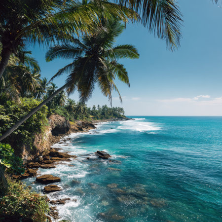 Experience the beauty of a serene tropical seascape featuring lush palm trees and a rocky shoreline under a clear blue sky, inviting relaxation and tranquility.の素材
