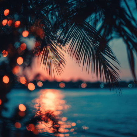 A stunning sunset creates a peaceful scene over calm waters, framed by silhouetted palm fronds and soft bokeh lights, perfect for capturing a serene and tropical ambiance.の素材