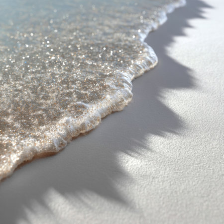A serene view of gentle ocean waves rolling onto a soft sandy shore. The sunlight creates beautiful reflections, capturing the tranquility of a perfect beach day.の素材