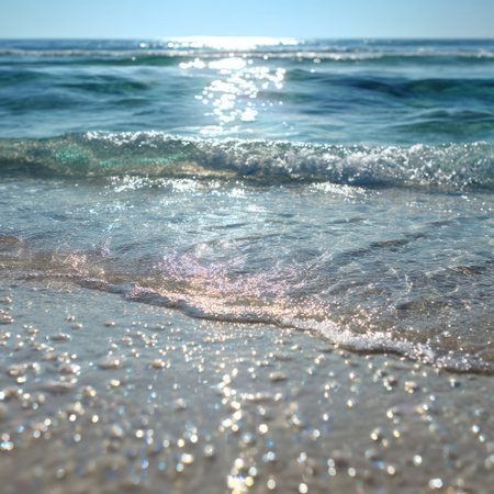 A captivating view of gentle ocean waves washing onto a sandy beach, illuminated by bright sunlight, perfect for evoking a sense of peace and tranquility in nature.の素材