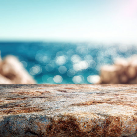 A smooth stone surface stretches out in the foreground, complementing the blurred blue hues of the ocean waters. The bright sunlight enhances the tranquil coastal ambiance.の素材