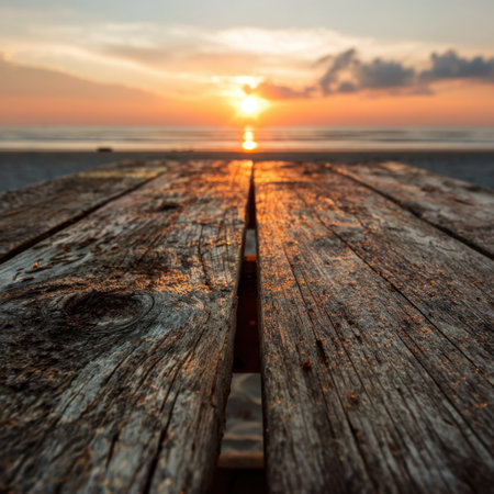 A captivating view of a serene sunset over a tranquil beach, featuring a weathered wooden table that enhances the natural beauty and tranquility of the scene.の素材