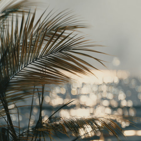 A beautiful scene capturing the soft glow of sunlight reflecting on water, framed by silhouetted tropical leaves, evoking a serene atmosphere for nature enthusiasts.の素材