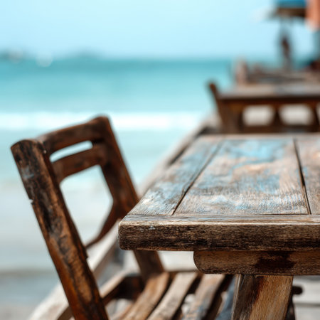 A rustic wooden table set against a serene beach backdrop, inviting relaxation and summer gatherings. The gentle waves create a peaceful atmosphere perfect for leisure.の素材