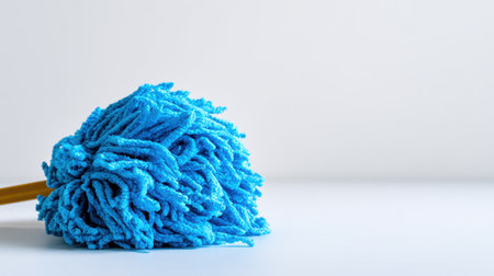 A bright blue mop resting on a smooth surface, embodying cleanliness and simplicity, evoking themes of home maintenance and effective cleaning solutions in modern settings.の素材