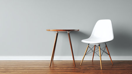 A minimalist interior scene featuring a round wooden table and a chic white chair set against a soft gray wall, perfect for showcasing modern decor ideas and creating a serene atmosphere.の素材