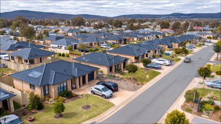 Explore a peaceful suburban neighborhood through an aerial view, showcasing modern houses with well-maintained streets and lush greenery, perfect for family living.の素材