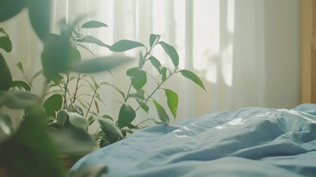 A tranquil bedroom setting featuring soft blue bedding and lush green plants near a window, bathed in natural light, perfect for relaxation and a peaceful atmosphere.の素材